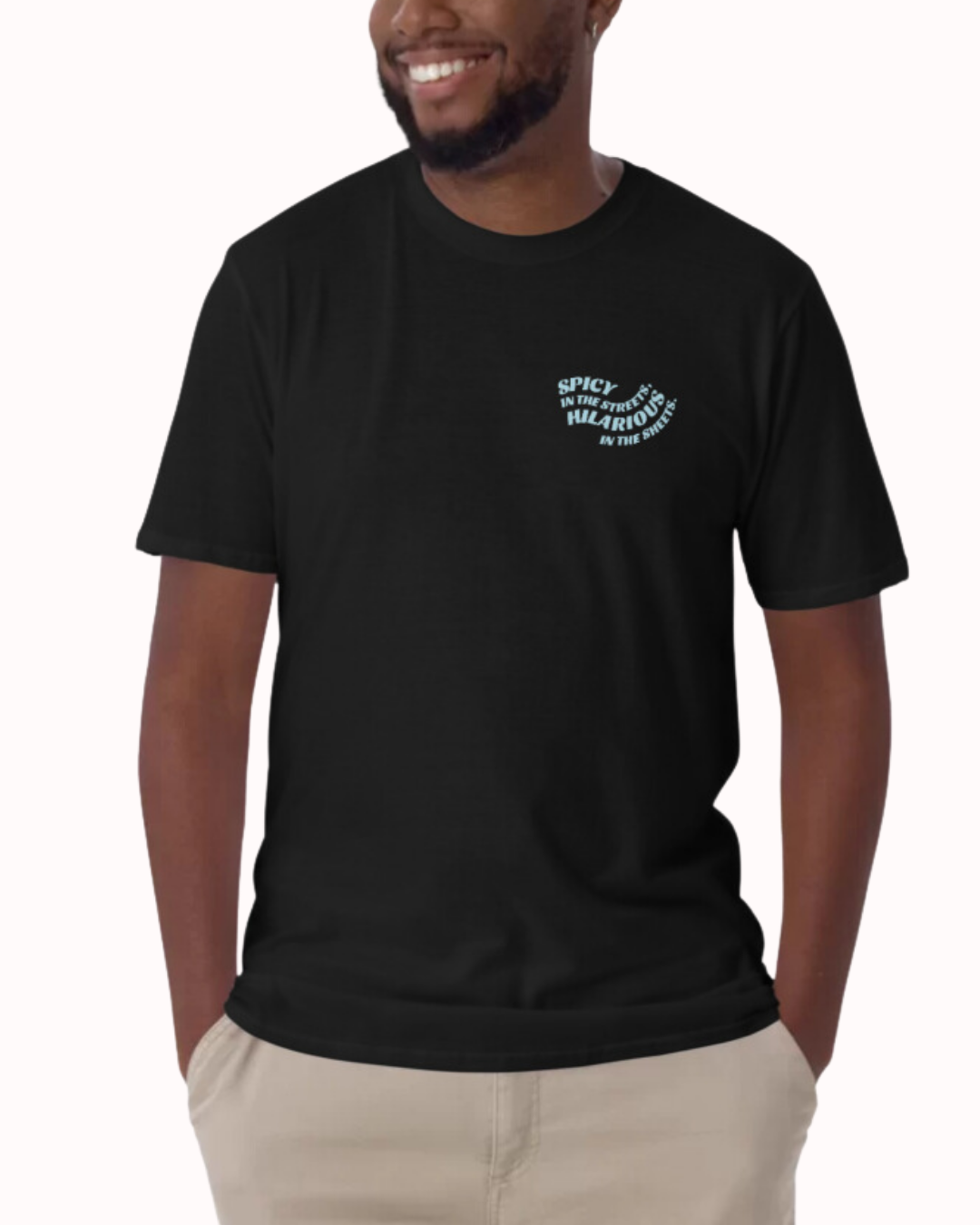 Front view of a black T-Shirt worn by a smiling man, featuring the phrase 'Spicy in the streets, Hilarious in the sheets' on the chest and back. Perfect for fans of funny merchandise, bold humor, and witty sarcasm.