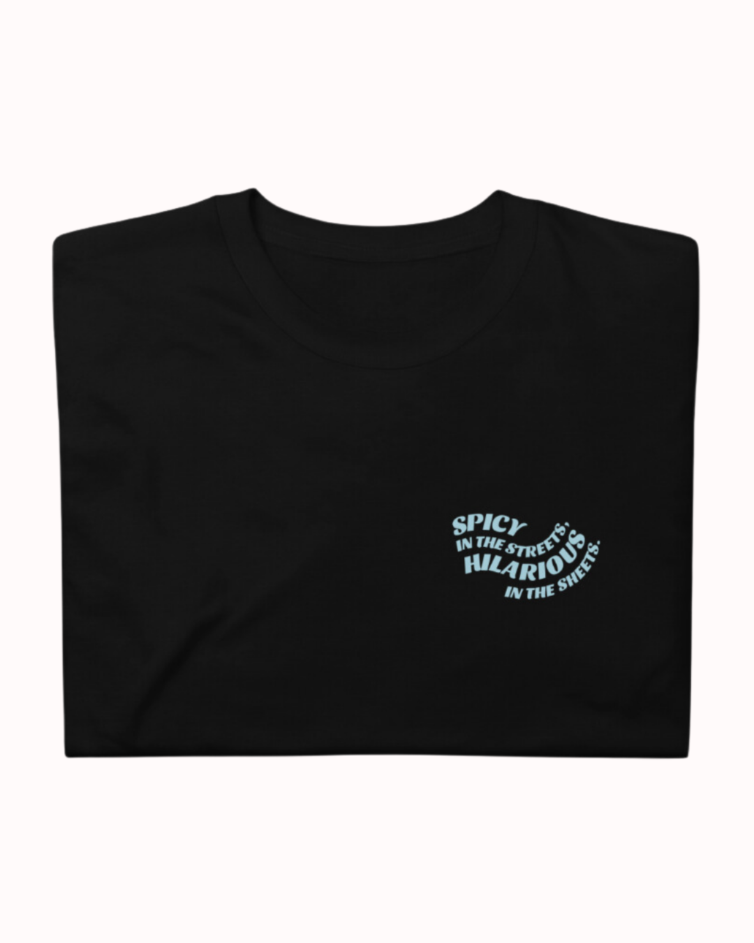 Folded black T-Shirt featuring the ironic phrase 'Spicy in the streets, Hilarious in the sheets'. Perfect for fans of funny merchandise, bold humor, and witty sarcasm.