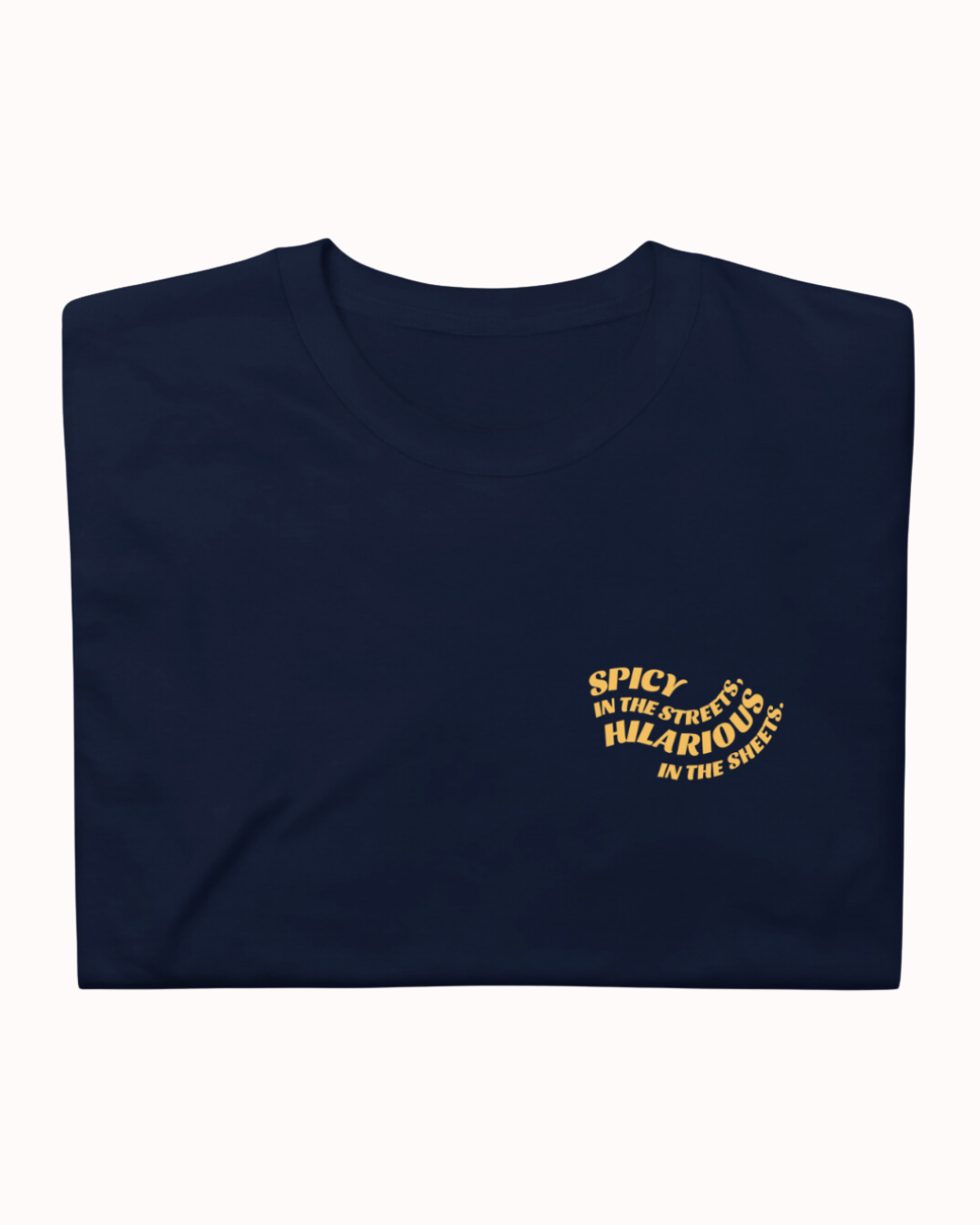 Folded navy T-Shirt featuring the ironic phrase 'Spicy in the streets, Hilarious in the sheets'. Perfect for fans of funny merchandise, bold humor, and witty sarcasm.