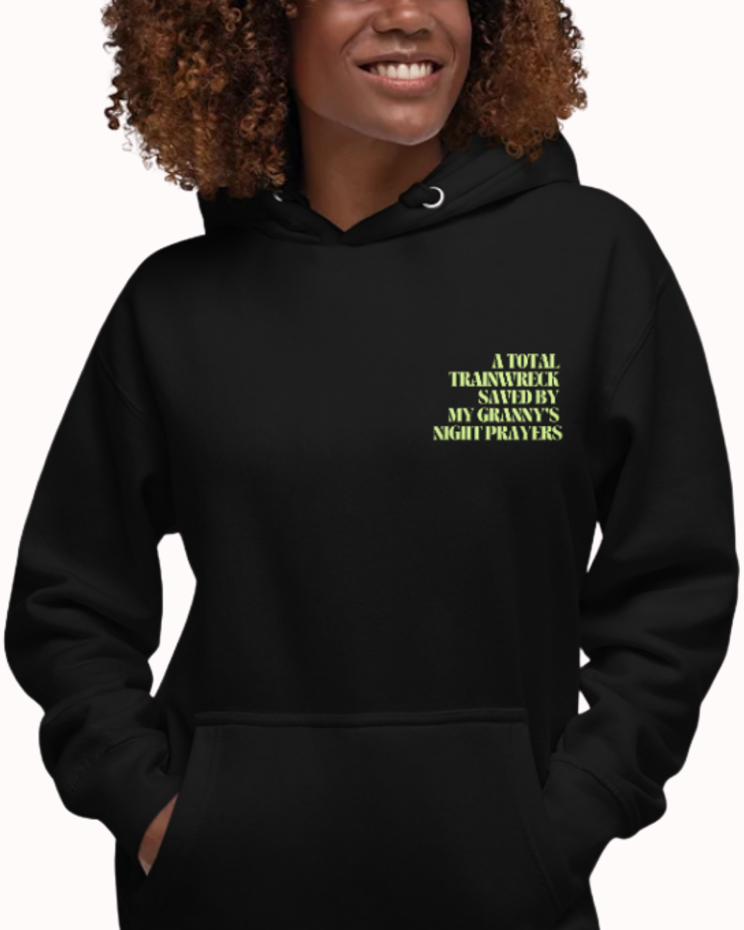 Front view of a Black hoodie worn by a smiling woman, featuring the phrase "A total trainwreck saved my granny's night prayers" on the chest and back. Perfect for fans of funny merchandise, bold humor, and witty sarcasm.