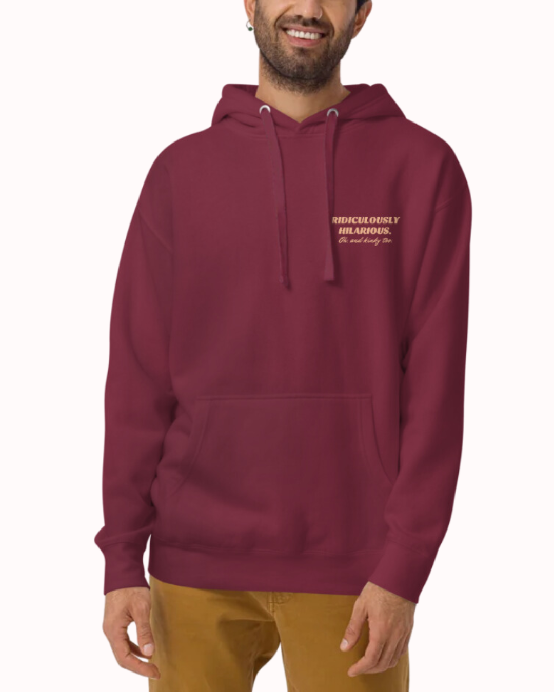 Front view of a maroon hoodie worn by a smiling man, featuring the phrase 'Ridiculously hilarious. Oh, and kinky too' on the chest and back. Perfect for fans of funny merchandise, bold humor, and witty sarcasm.
