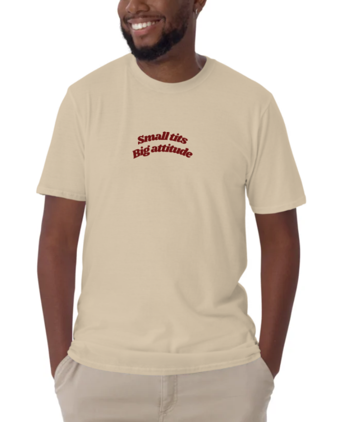 Front view of a Sand t-shirt worn by a smiling man, featuring the phrase "Small tits. Big attitude" on the chest and back. Perfect for fans of funny merchandise, bold humor, and witty sarcasm.