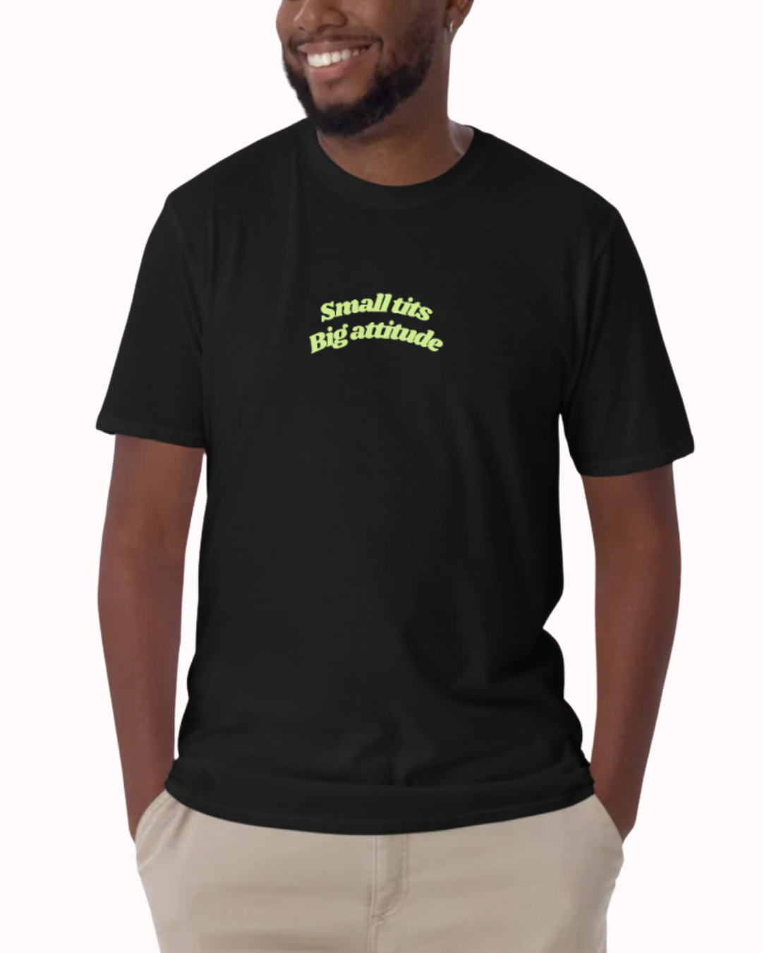 Front view of a Black t-shirt worn by a smiling man, featuring the phrase "Small tits. Big attitude" on the chest and back. Perfect for fans of funny merchandise, bold humor, and witty sarcasm.