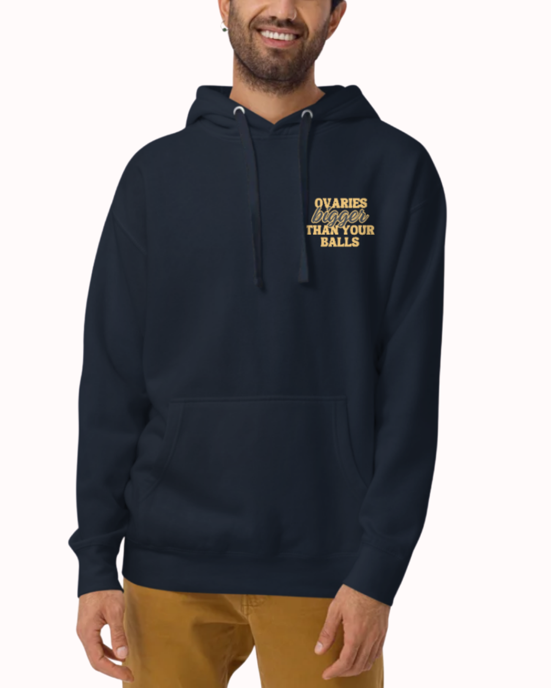 Front view of a navy blazer hoodie worn by a smiling man, featuring the phrase 'Ovaries bigger than your balls' on the chest and back. Perfect for fans of funny merchandise, bold humor, and witty sarcasm.