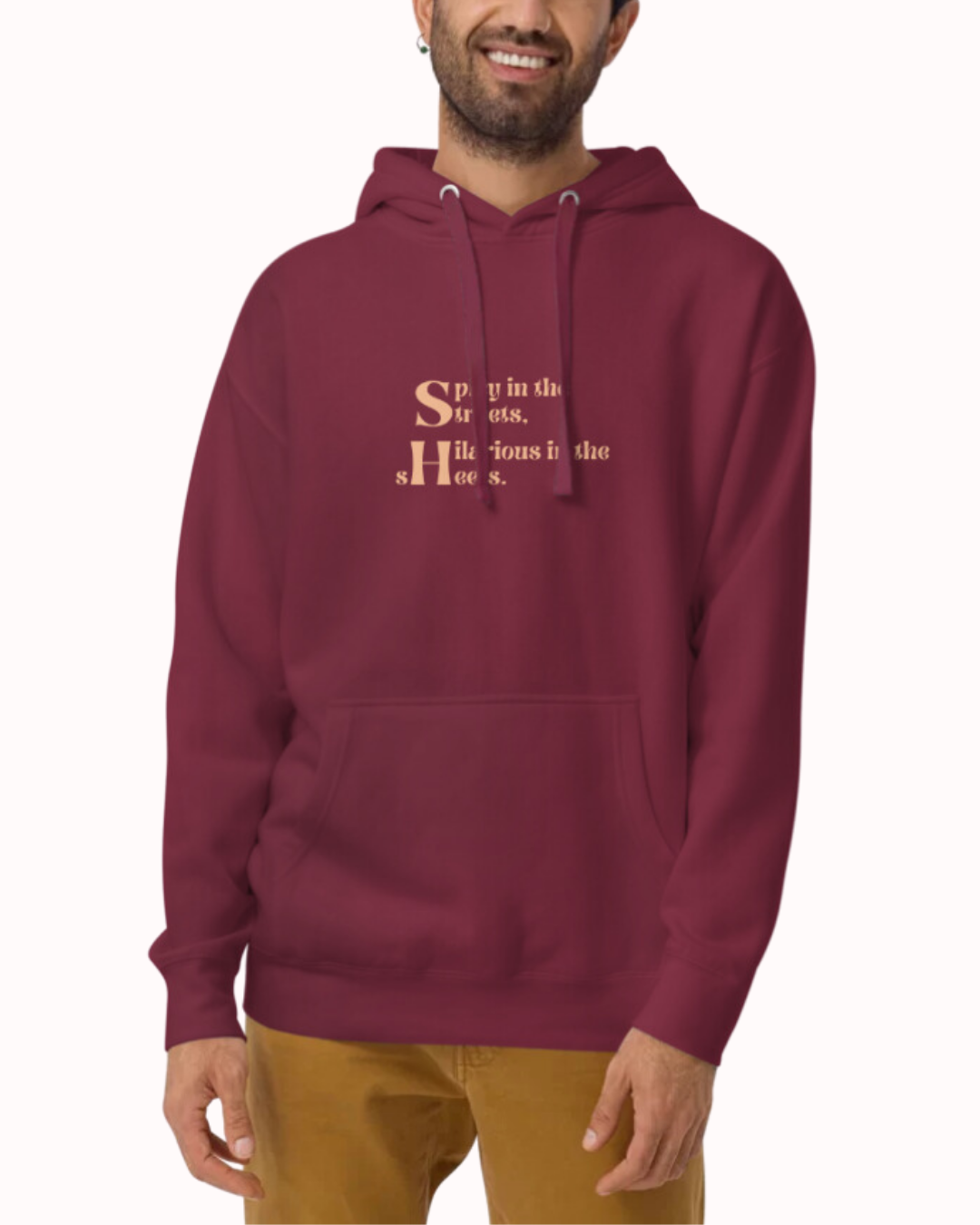 Front view of a maroon hoodie worn by a smiling man, featuring the phrase 'Spicy in the streets, Hilarious in the sheets' on the chest. Perfect for fans of funny merchandise, bold humor, and witty sarcasm.