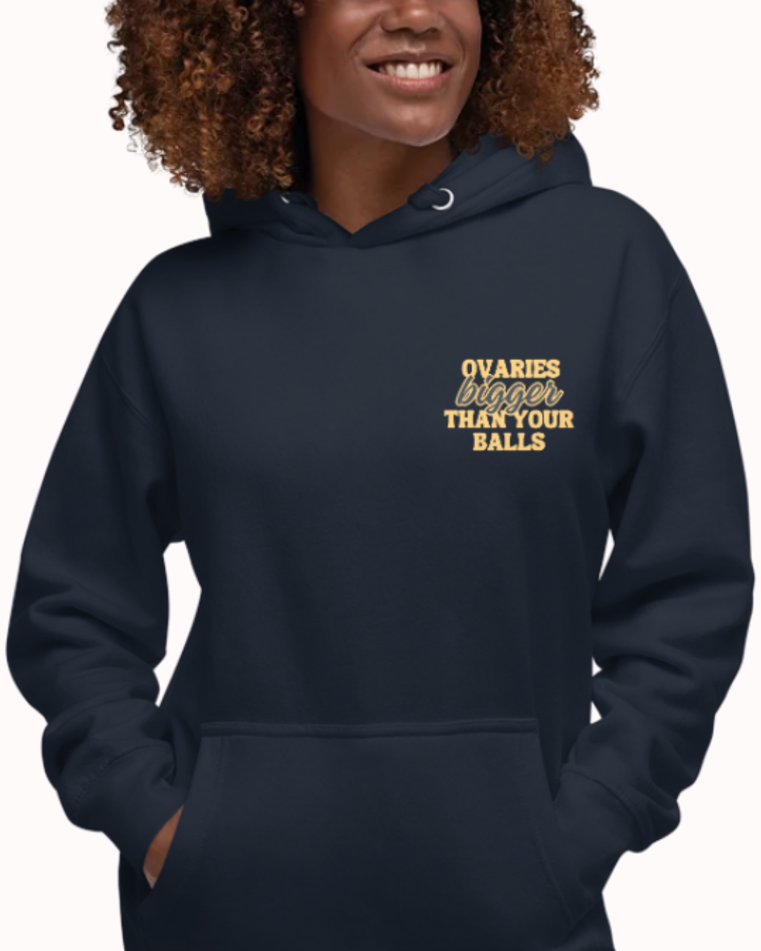 Front view of a navy blazer hoodie worn by a smiling woman, featuring the phrase 'Ovaries bigger than your balls' on the chest and back. Perfect for fans of funny merchandise, bold humor, and witty sarcasm.