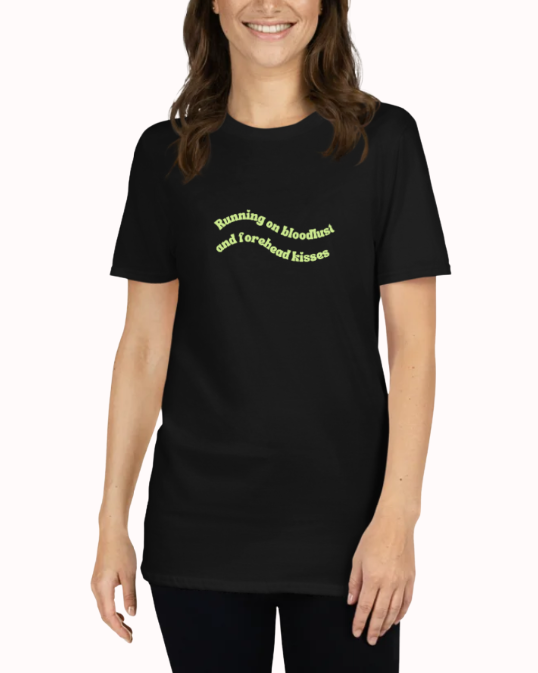 Front view of a Black t-shirt worn by a smiling woman, featuring the phrase "Running on bloodlust and forehead kisses" on the chest and back. Perfect for fans of funny merchandise, bold humor, and witty sarcasm.
