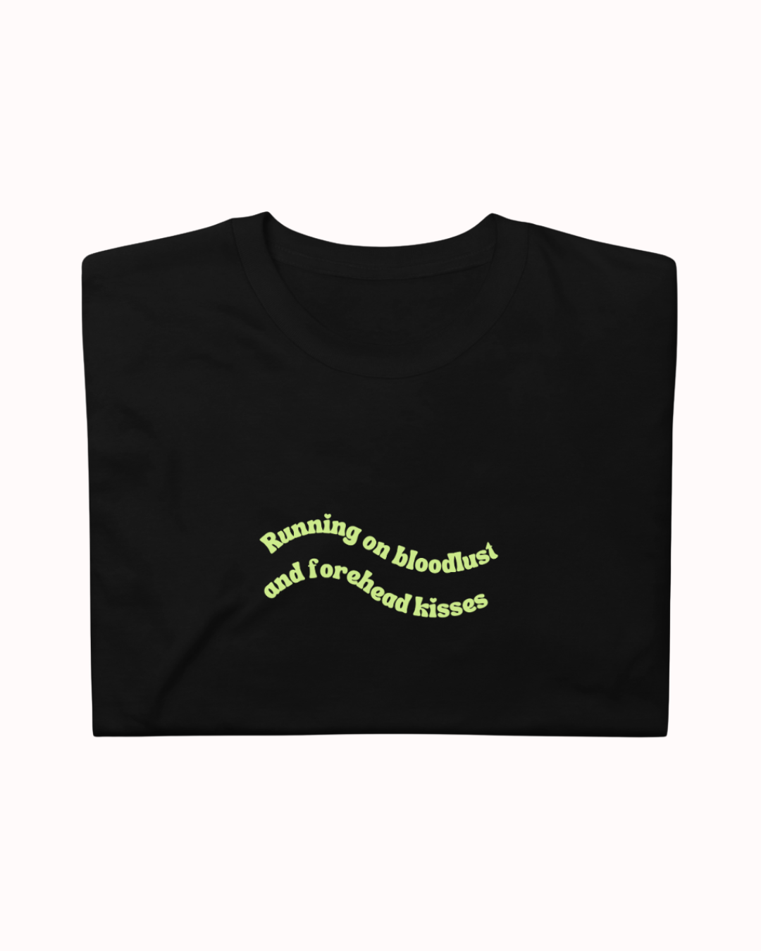Folded Black t-shirt featuring the ironic phrase "Running on bloodlust and forehead kisses". Perfect for fans of funny merchandise, bold humor, and witty sarcasm.