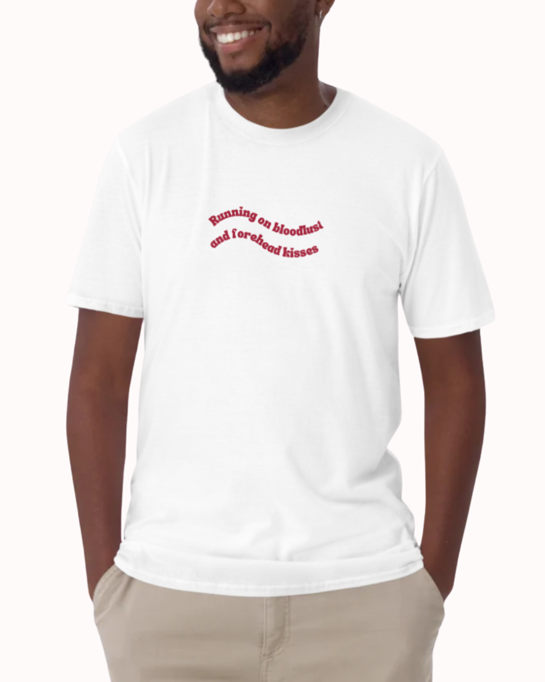 Front view of a White t-shirt worn by a smiling man, featuring the phrase "Running on bloodlust and forehead kisses" on the chest and back. Perfect for fans of funny merchandise, bold humor, and witty sarcasm.