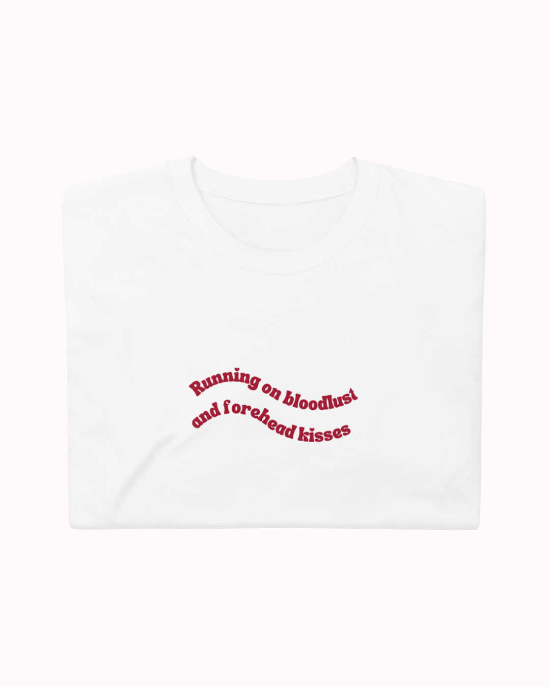 Folded White t-shirt featuring the ironic phrase "Running on bloodlust and forehead kisses". Perfect for fans of funny merchandise, bold humor, and witty sarcasm.