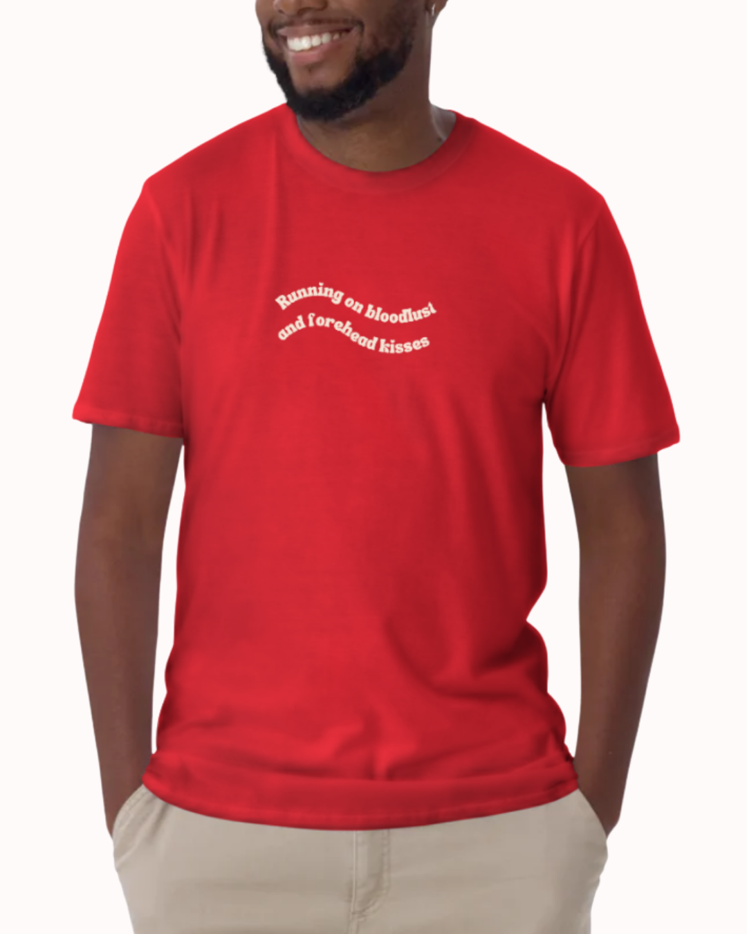 Front view of a Red t-shirt worn by a smiling man, featuring the phrase "Running on bloodlust and forehead kisses" on the chest and back. Perfect for fans of funny merchandise, bold humor, and witty sarcasm.