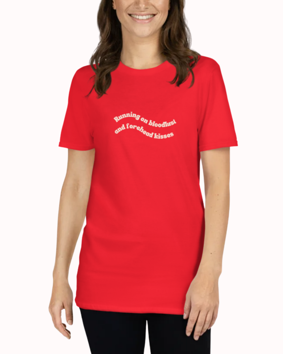 Front view of a Red t-shirt worn by a smiling woman, featuring the phrase "Running on bloodlust and forehead kisses" on the chest and back. Perfect for fans of funny merchandise, bold humor, and witty sarcasm.