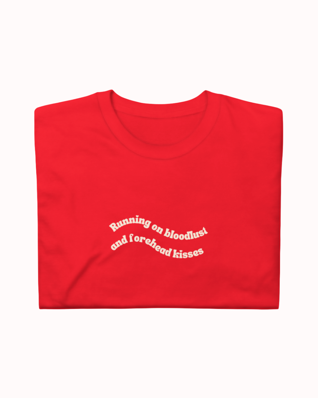 Folded Red t-shirt featuring the ironic phrase "Running on bloodlust and forehead kisses". Perfect for fans of funny merchandise, bold humor, and witty sarcasm.