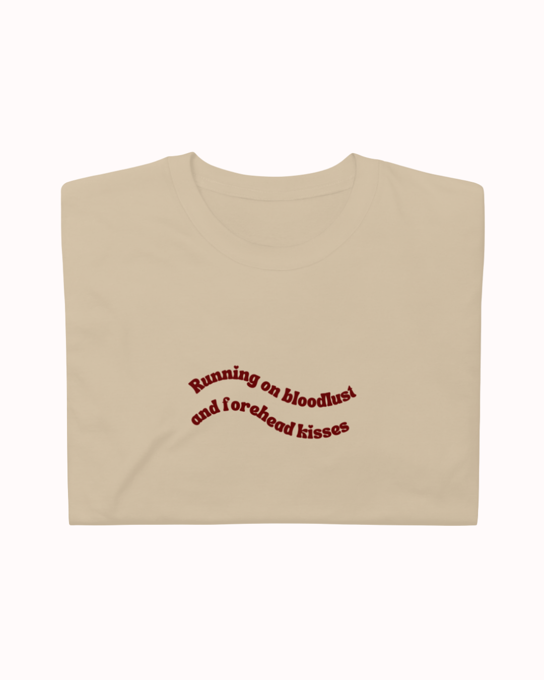 Folded Sand t-shirt featuring the ironic phrase "Running on bloodlust and forehead kisses". Perfect for fans of funny merchandise, bold humor, and witty sarcasm.