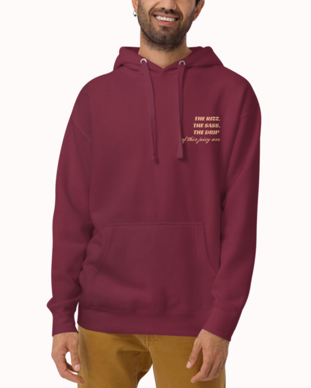 Front view of a maroon hoodie worn by a smiling man, featuring the phrase 'The Rizz. The Sass. The Drip of this Juicy Ass' on the chest and back. Perfect for fans of funny merchandise, bold humor, and witty sarcasm.
