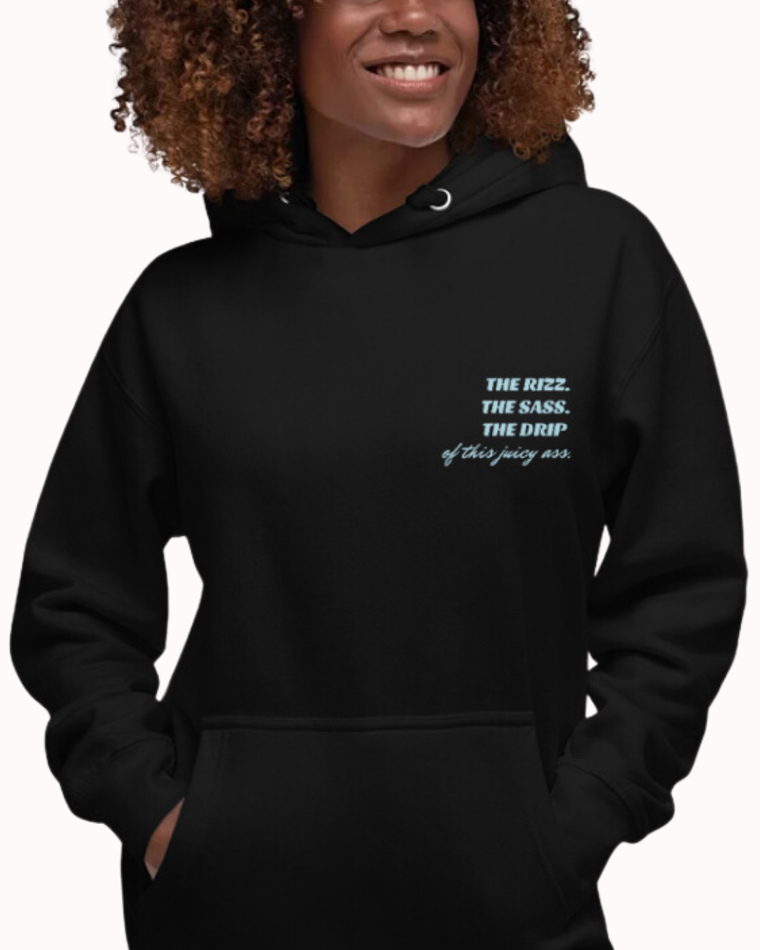 Front view of a black hoodie worn by a smiling woman, featuring the phrase 'The Rizz. The Sass. The Drip of this Juicy Ass' on the chest and back. Perfect for fans of funny merchandise, bold humor, and witty sarcasm.