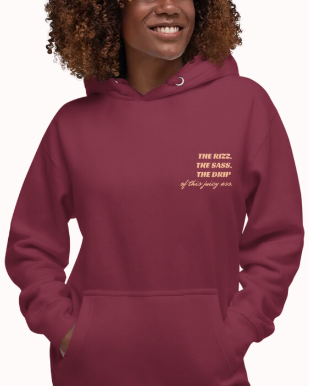 Front view of a maroon hoodie worn by a smiling woman, featuring the phrase 'The Rizz. The Sass. The Drip of this Juicy Ass' on the chest and back. Perfect for fans of funny merchandise, bold humor, and witty sarcasm.