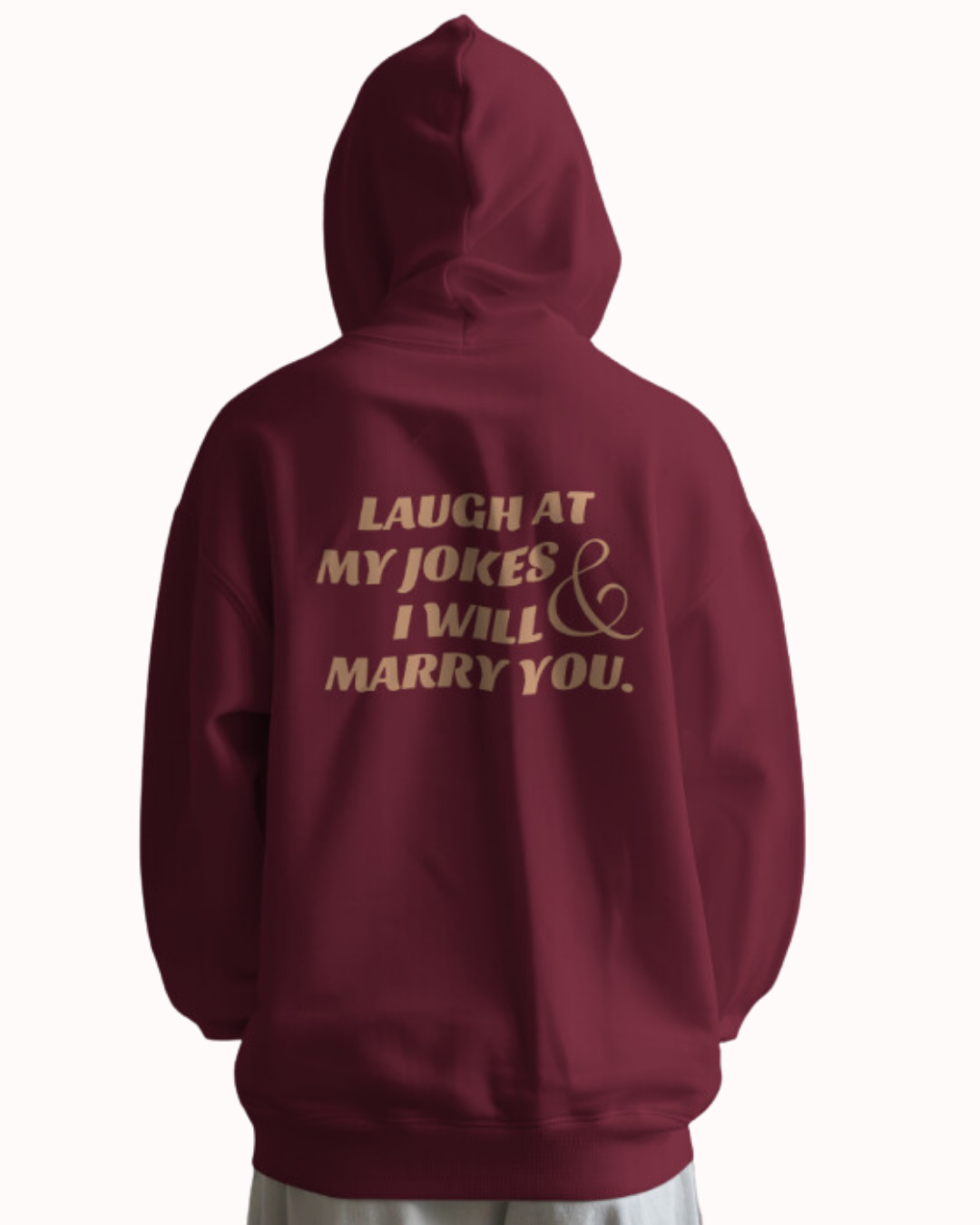 Back view of a maroon hoodie featuring the phrase 'Laugh at my jokes and I will marry you' on the back. Perfect for fans of funny merchandise, bold humor, and witty sarcasm.
