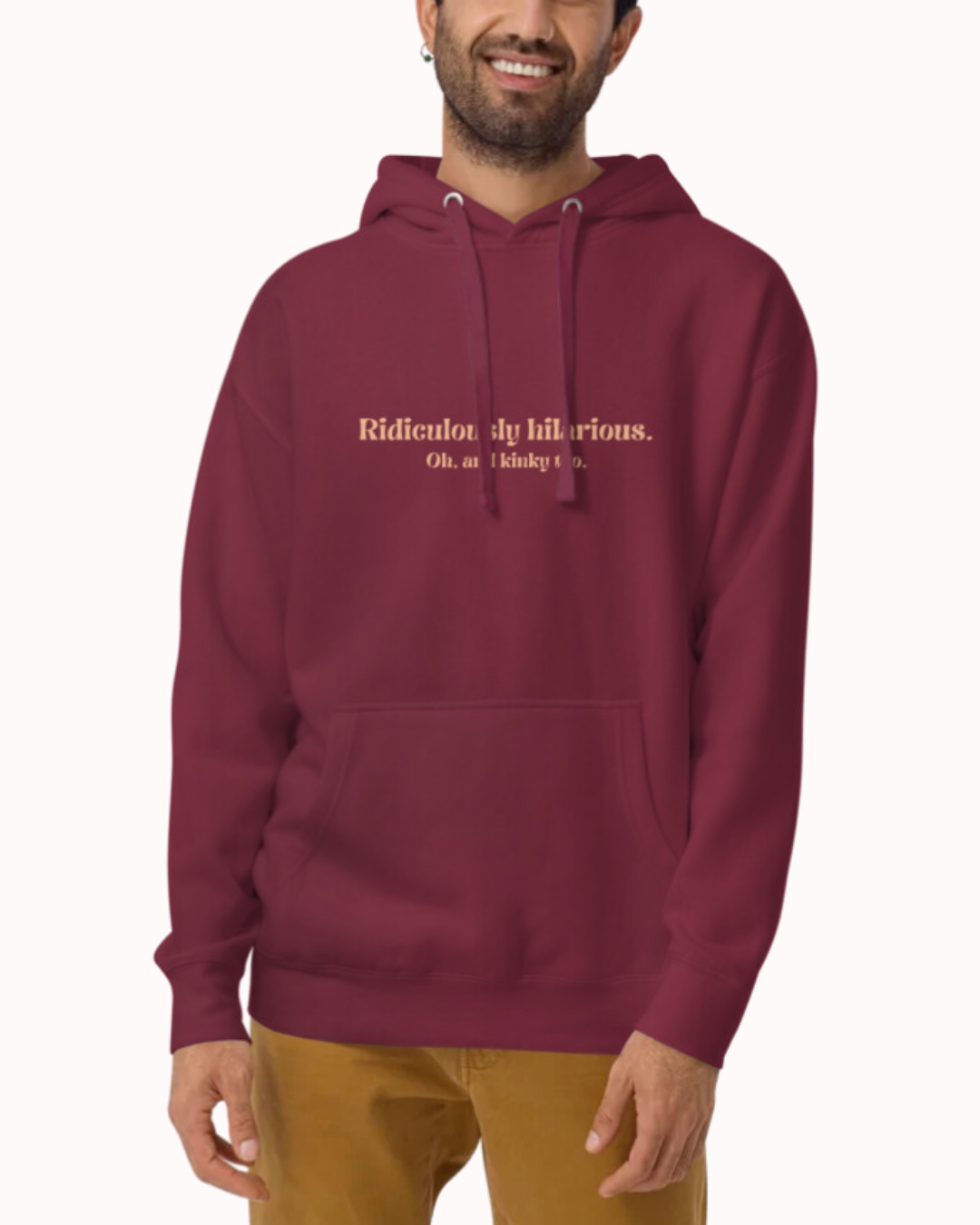 Front view of a maroon hoodie worn by a smiling man, featuring the phrase 'Ridiculously hilarious. Oh, and kinky too' on the chest. Perfect for fans of funny merchandise, bold humor, and witty sarcasm.