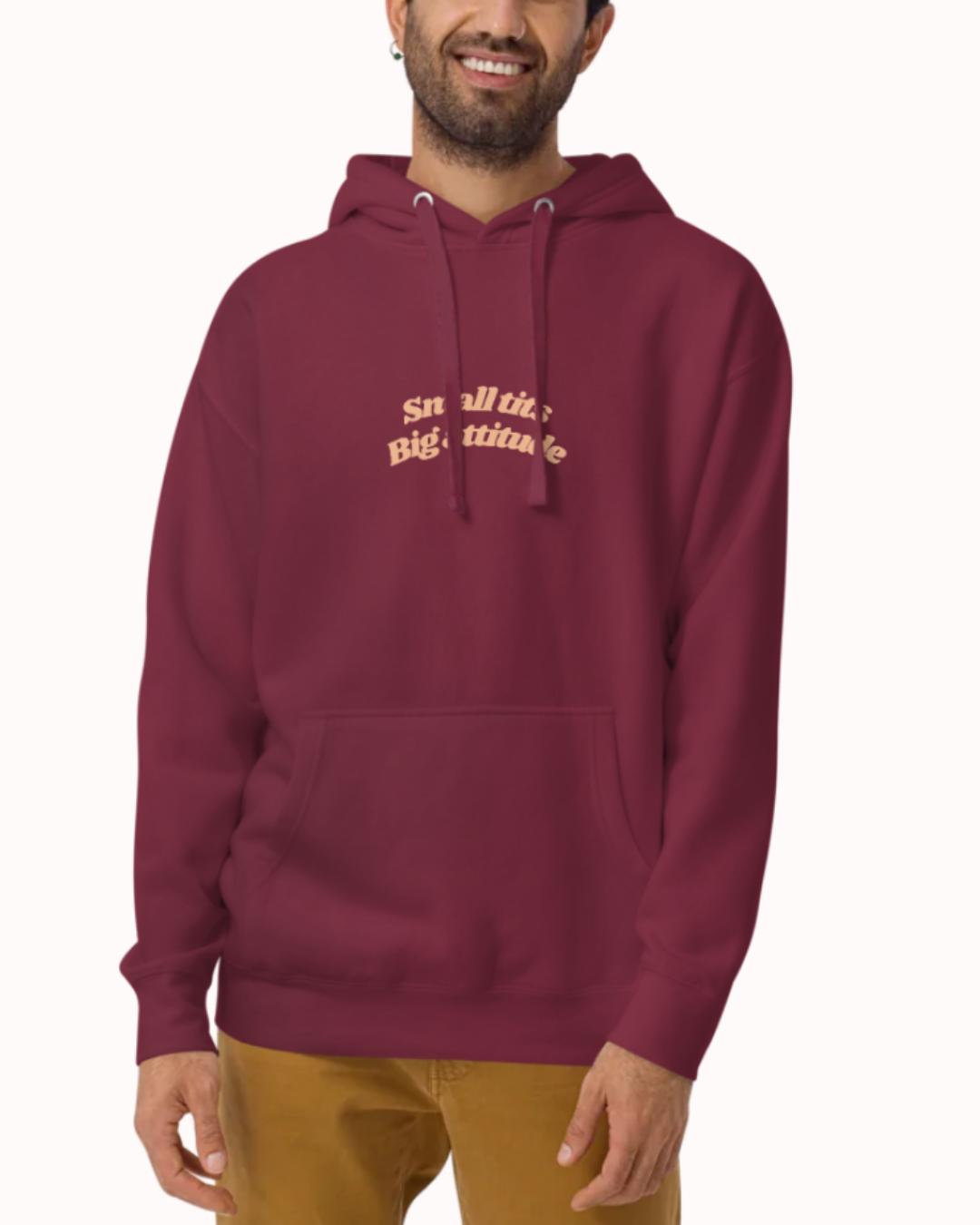 Front view of a Maroon hoodie worn by a smiling man, featuring the phrase "Small tits. Big attitude" on the chest and back. Perfect for fans of funny merchandise, bold humor, and witty sarcasm.