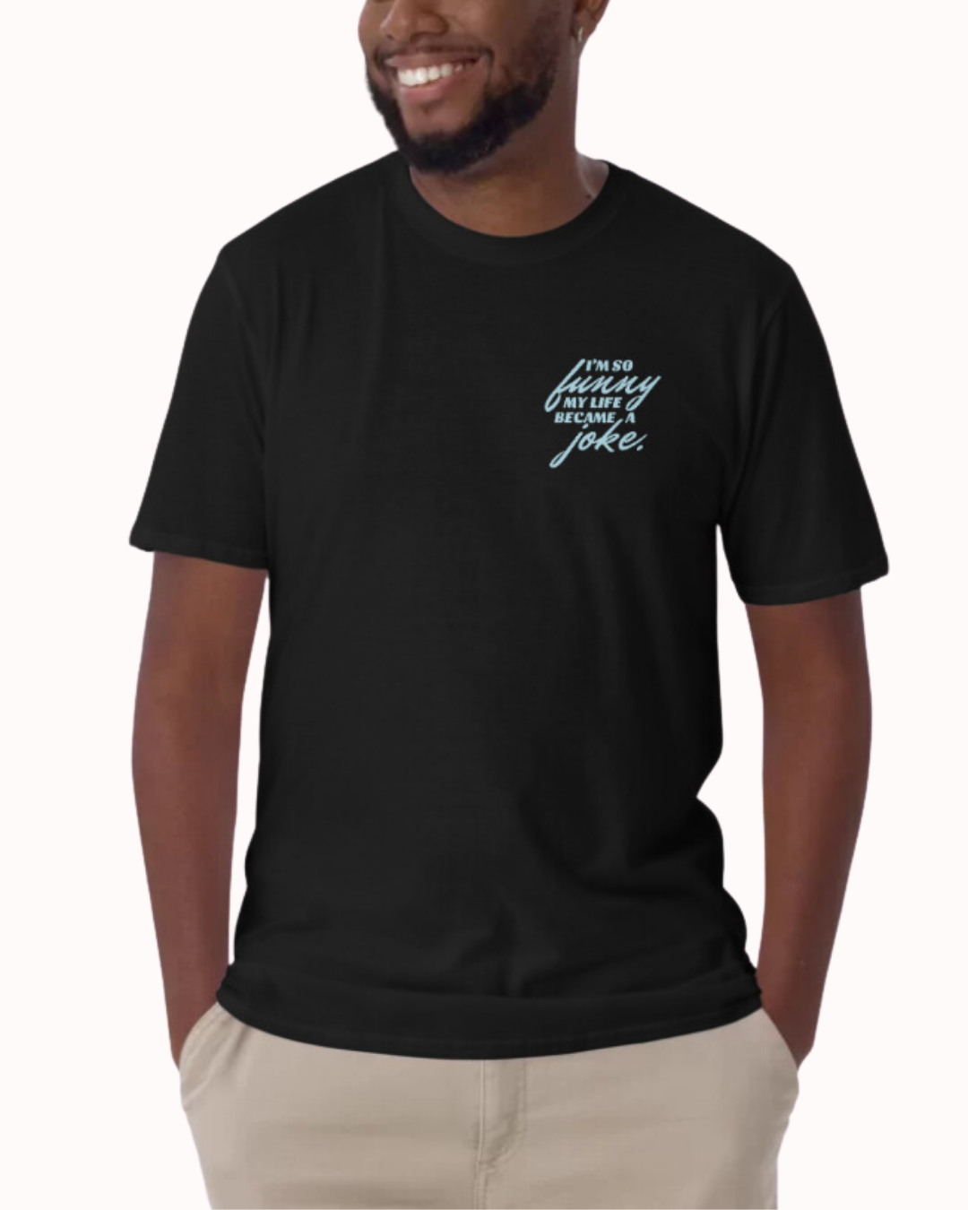 Front view of a black T-Shirt worn by a smiling man, featuring the phrase 'I'm so funny my life became a joke' on the chest and back. Perfect for fans of funny merchandise, bold humor, and witty sarcasm.