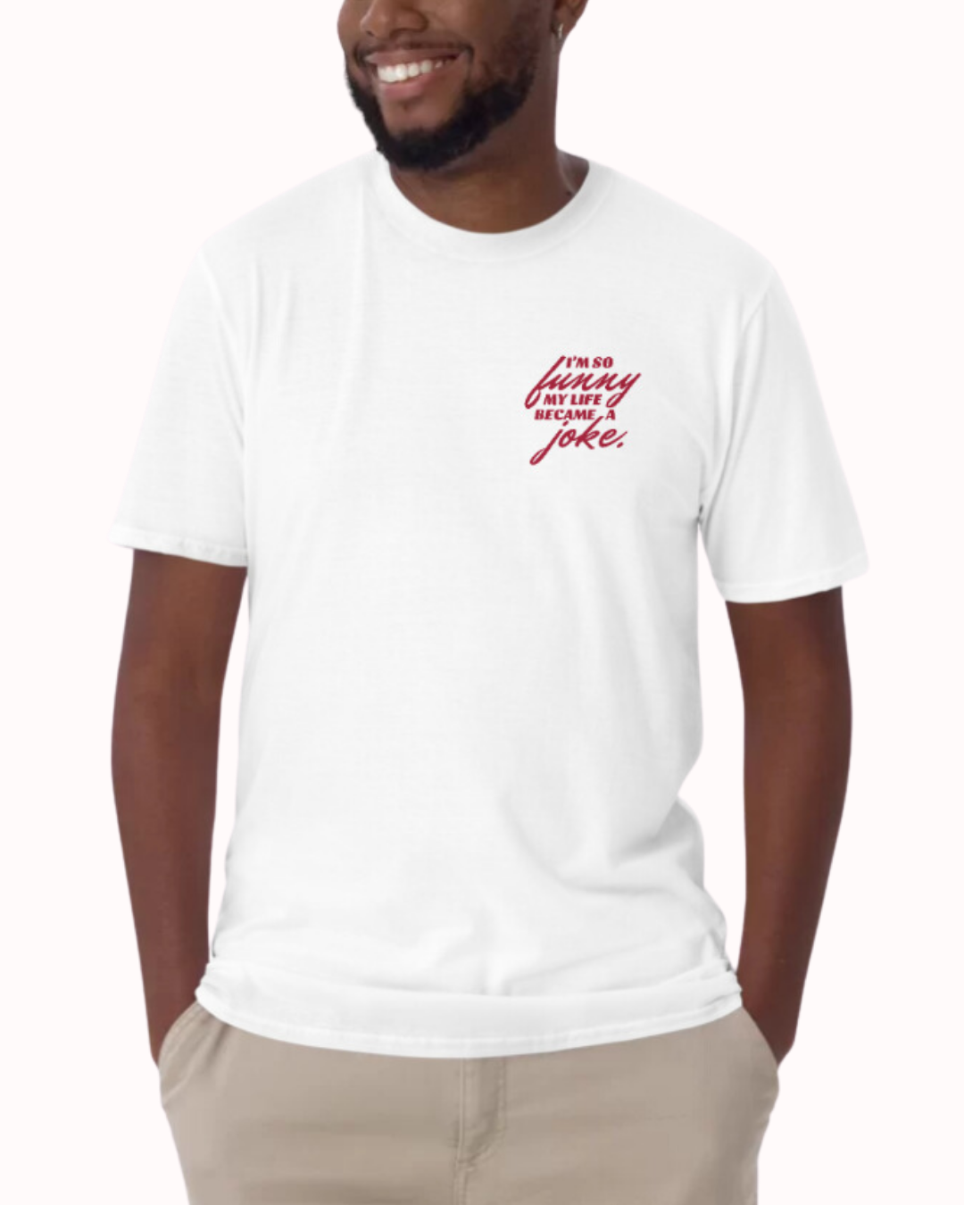 Front view of a white T-Shirt worn by a smiling man, featuring the phrase 'I'm so funny my life became a joke' on the chest and back. Perfect for fans of funny merchandise, bold humor, and witty sarcasm.