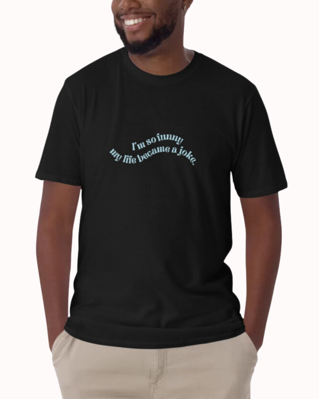 Front view of a black T-Shirt worn by a smiling man, featuring the phrase 'I'm so funny my life became a joke' on the chest. Perfect for fans of funny merchandise, bold humor, and witty sarcasm.