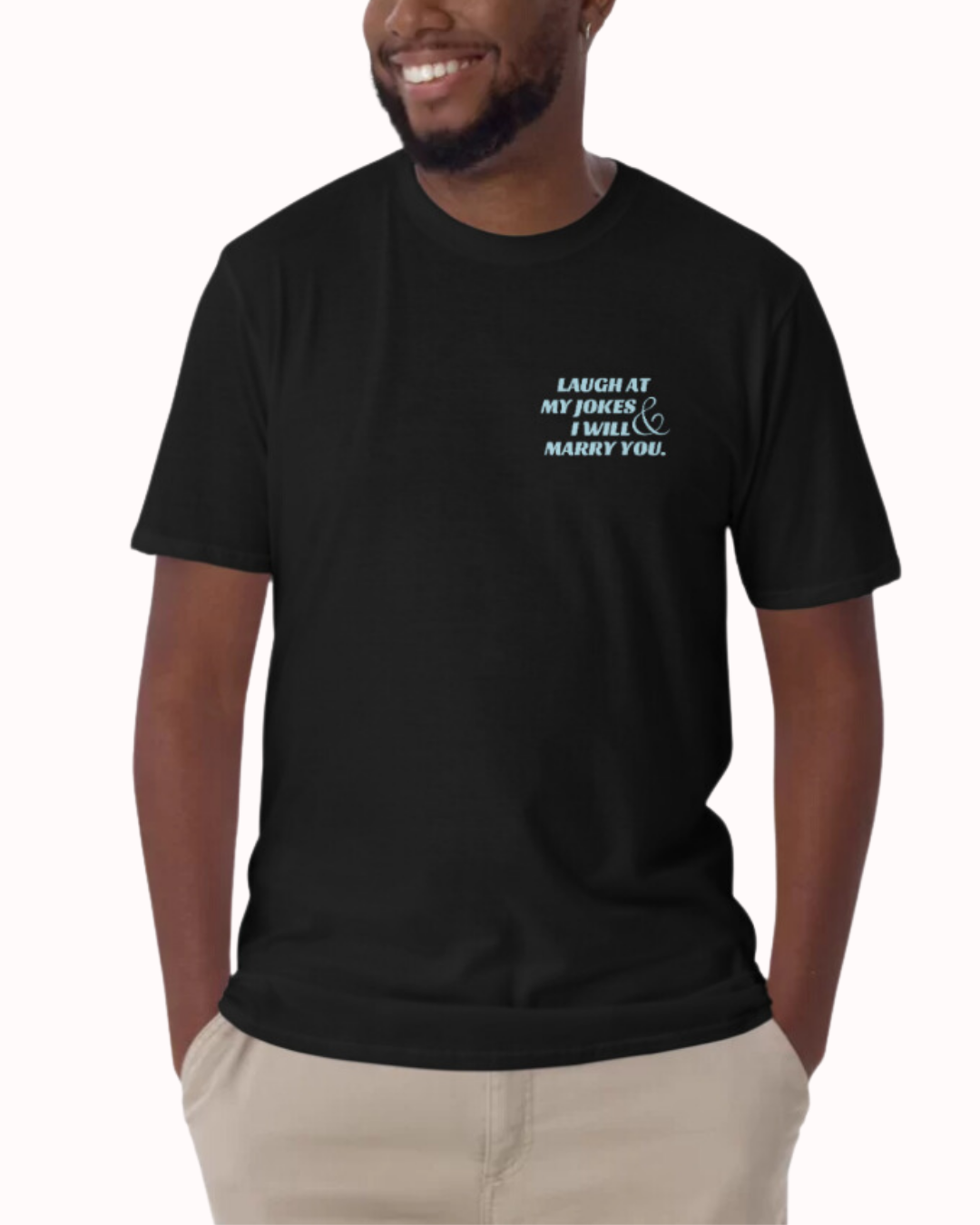 Front view of a black T-Shirt worn by a smiling man, featuring the phrase 'Laugh at my jokes and I will marry you' on the chest and back. Perfect for fans of funny merchandise, bold humor, and witty sarcasm.