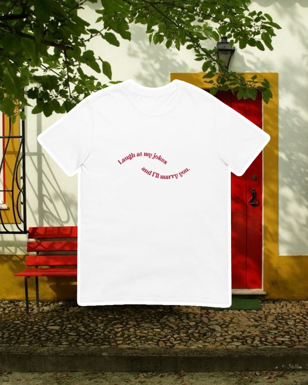 White T-Shirt with the phrase 'Laugh at my jokes and I will marry you' on the chest, displayed against an inviting space, perfect for relaxation or gathering with friends. A playful and bold design for fans of funny merchandise and sarcasm.