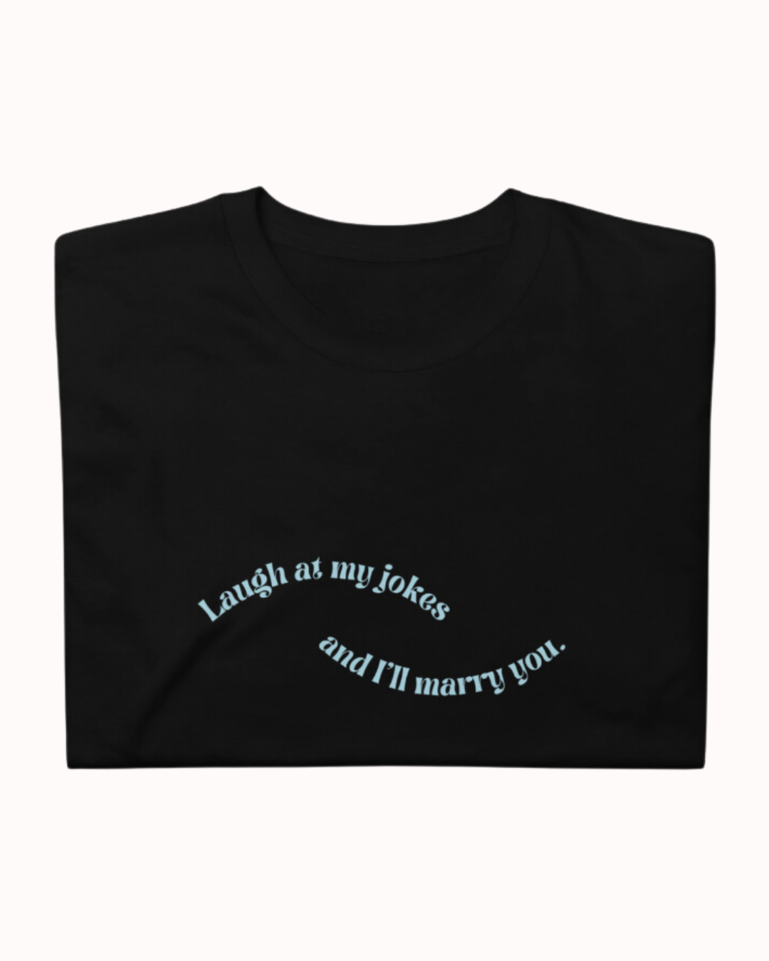 Folded black T-Shirt featuring the ironic phrase 'Laugh at my jokes and I will marry you'. Perfect for fans of funny merchandise, bold humor, and witty sarcasm.