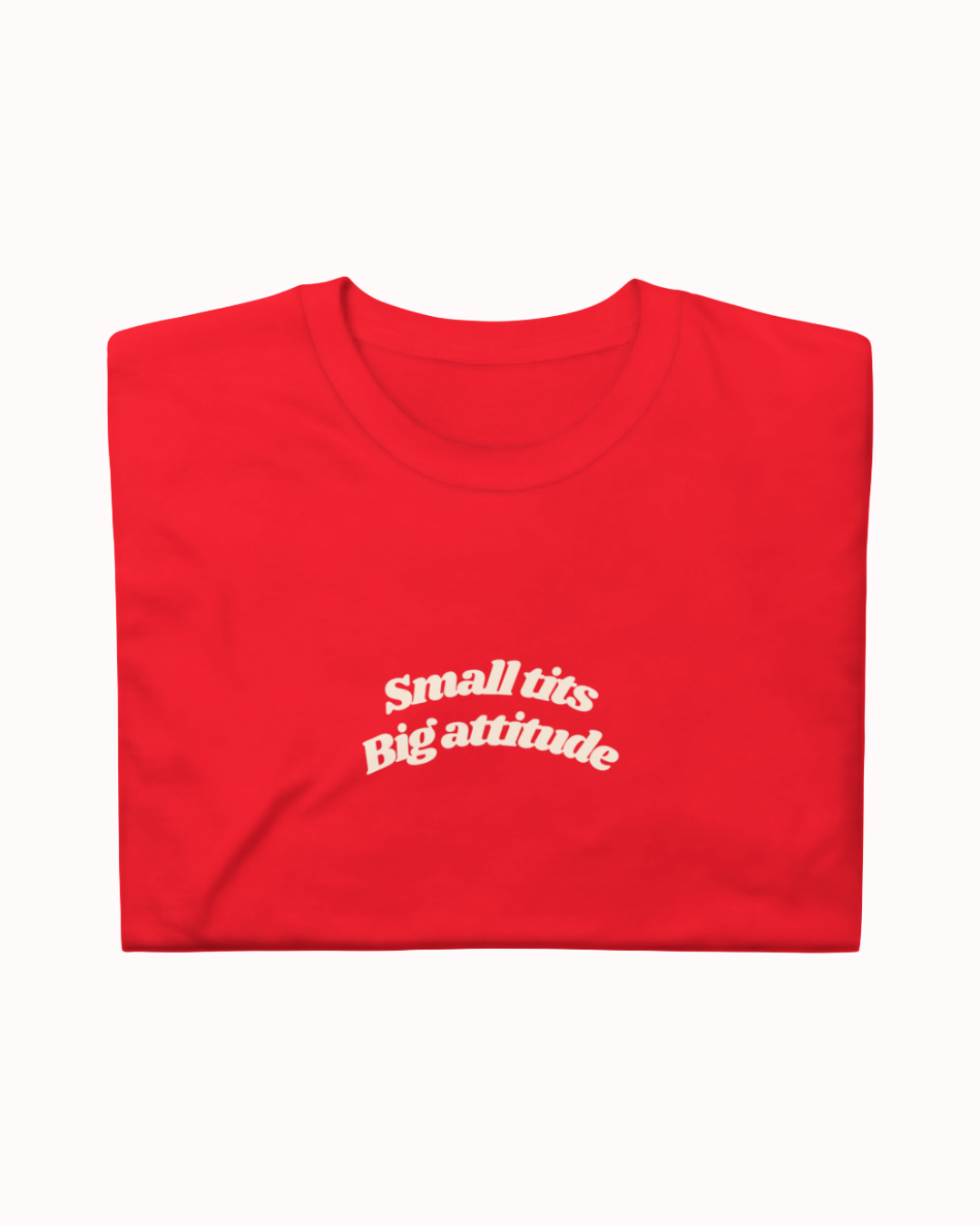 Folded Red t-shirt featuring the ironic phrase "Small tits. Big attitude". Perfect for fans of funny merchandise, bold humor, and witty sarcasm.
