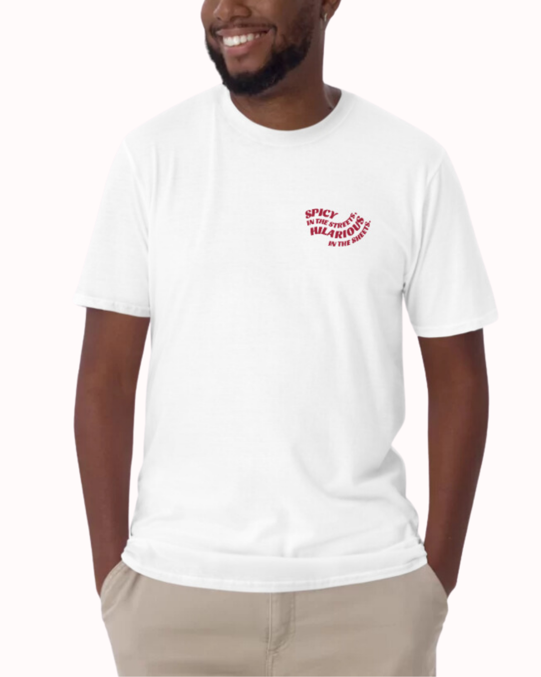 Front view of a white T-Shirt worn by a smiling man, featuring the phrase 'Spicy in the streets, Hilarious in the sheets' on the chest and back. Perfect for fans of funny merchandise, bold humor, and witty sarcasm.