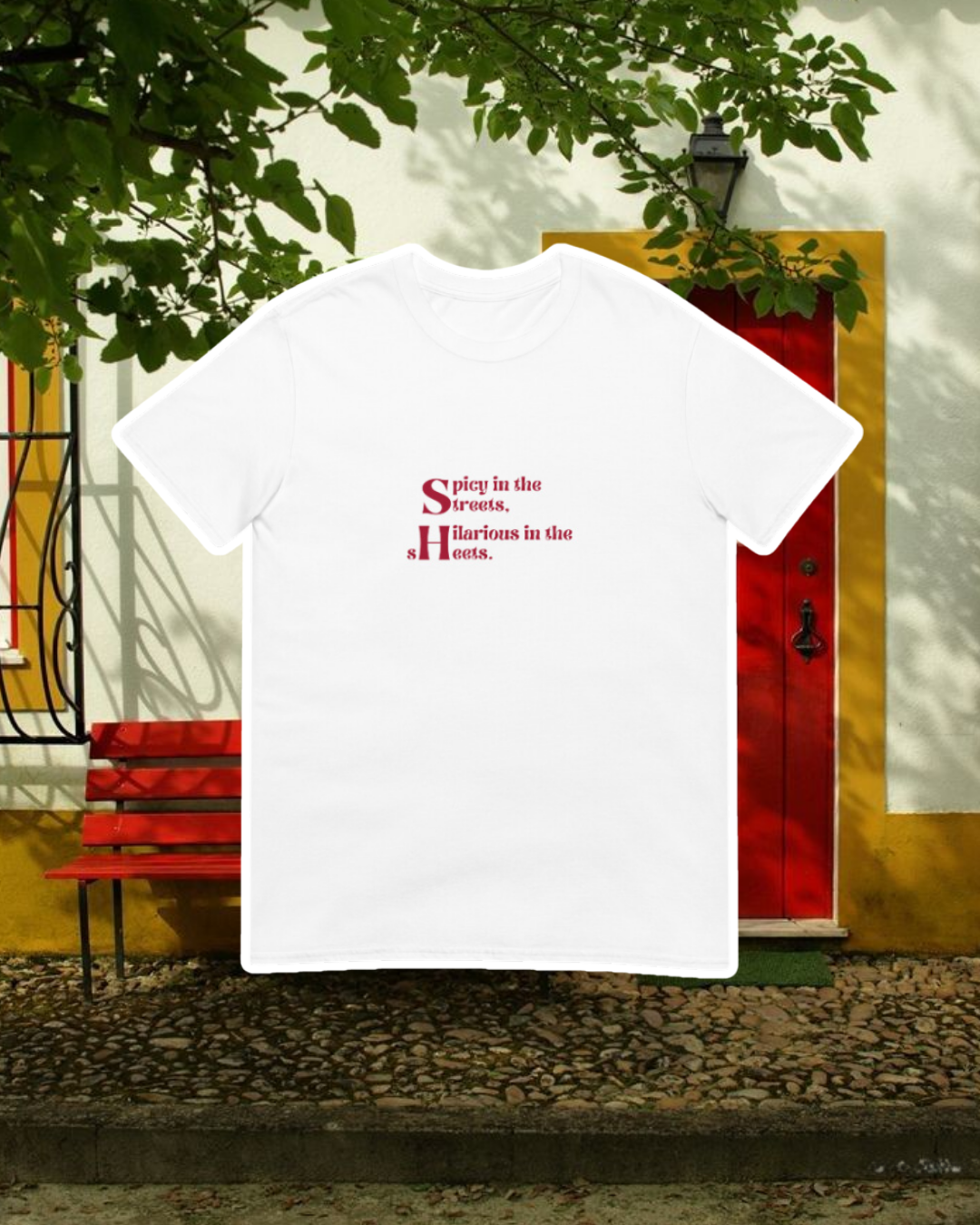 White T-Shirt with the phrase 'Spicy in the streets, Hilarious in the sheets' on the chest, displayed against an inviting space, perfect for relaxation or gathering with friends. A playful and bold design for fans of funny merchandise and sarcasm.
