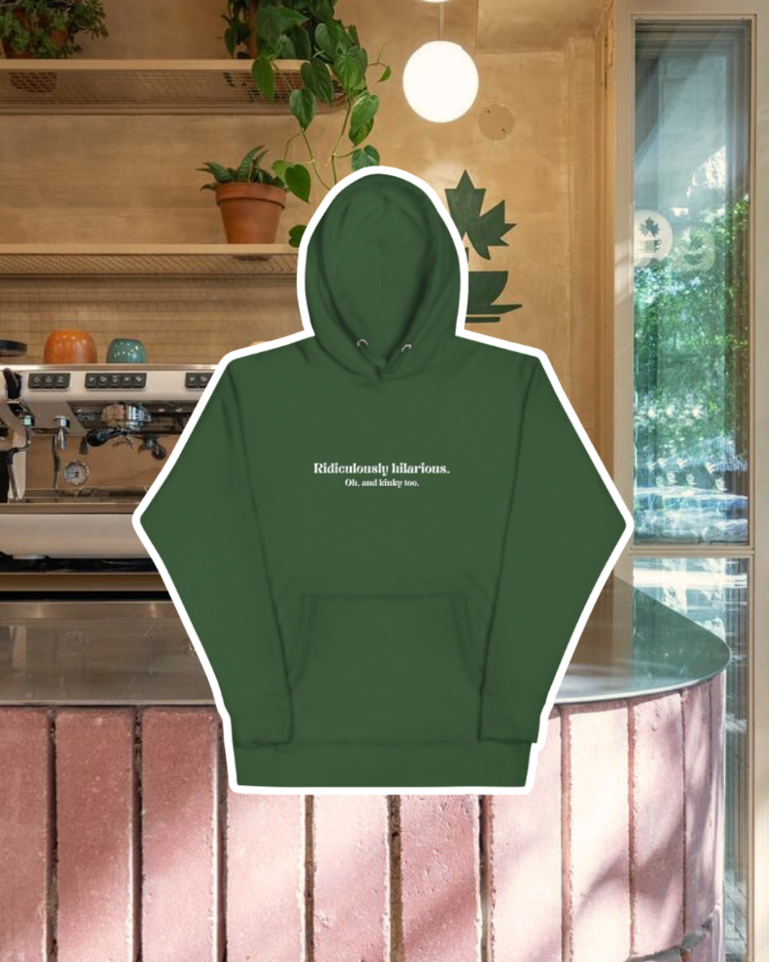 Forest green hoodie with the phrase 'Ridiculously hilarious. Oh, and kinky too' on the chest, displayed against a vibrant café-style backdrop with a pink counter and cozy decoration with plants. A playful and bold design for fans of funny merchandise and sarcasm.