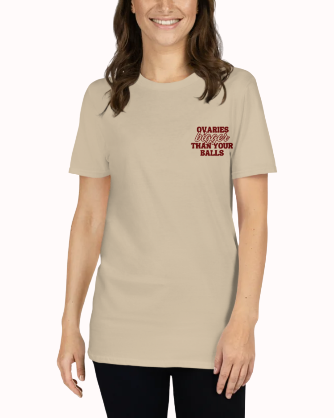 Front view of a Sand t-shirt worn by a smiling woman, featuring the phrase "Ovaries bigger than your balls" on the chest and back. Perfect for fans of funny merchandise, bold humor, and witty sarcasm.