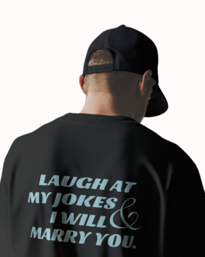 Back view of a black T-Shirt featuring the phrase 'Laugh at my jokes and I will marry you' on the back. Perfect for fans of funny merchandise, bold humor, and witty sarcasm.