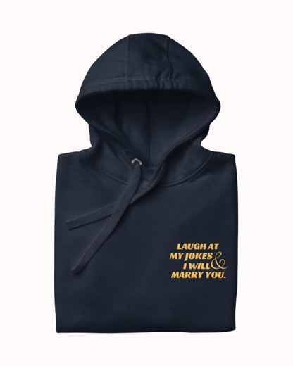 Folded navy blazer hoodie featuring the ironic phrase 'Laugh at my jokes and I will marry you'. Perfect for fans of funny merchandise, bold humor, and witty sarcasm.