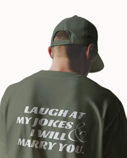 Back view of a military green T-Shirt featuring the phrase 'Laugh at my jokes and I will marry you' on the back. Perfect for fans of funny merchandise, bold humor, and witty sarcasm.