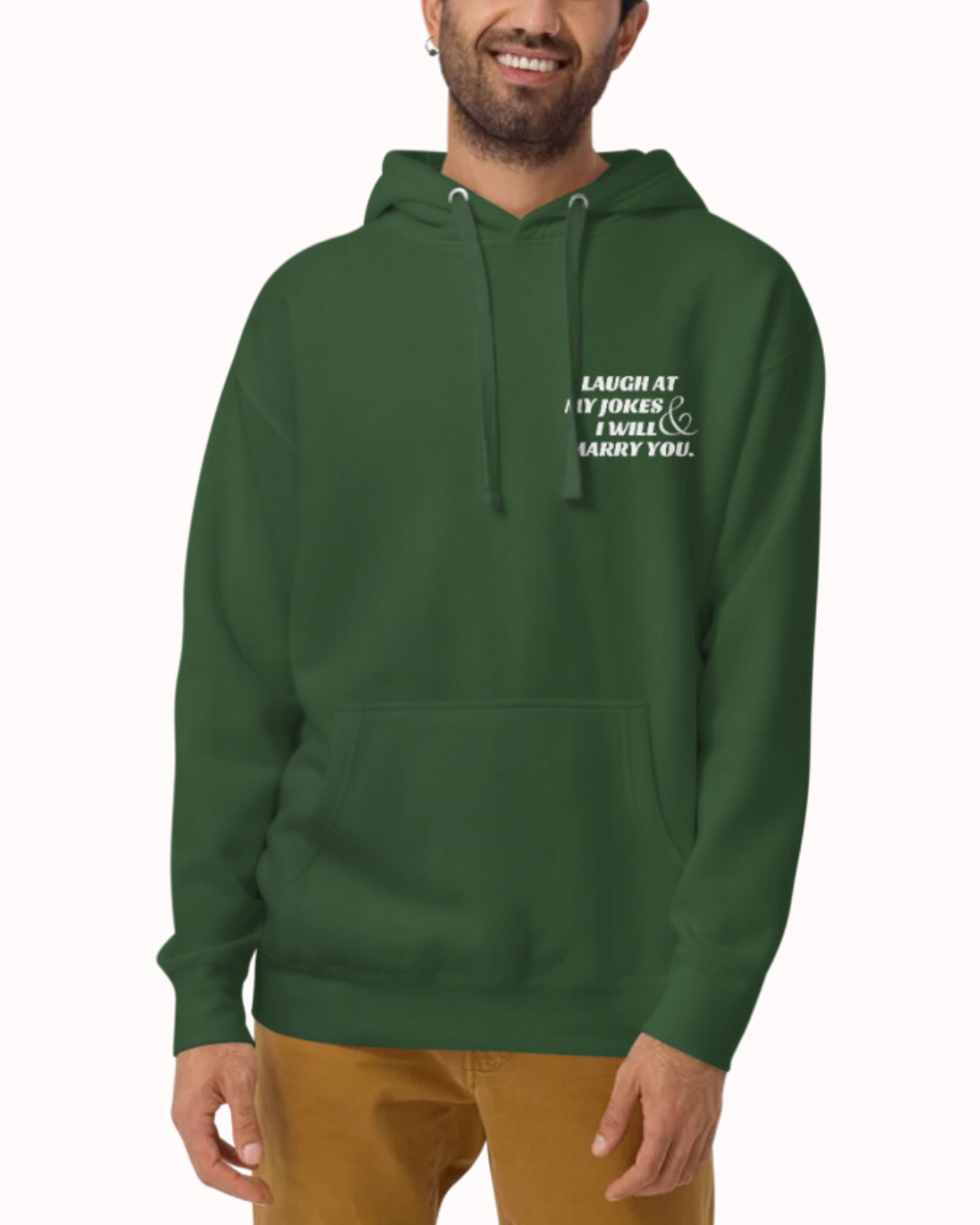 Front view of a forest green hoodie worn by a smiling man, featuring the phrase 'Laugh at my jokes and I will marry you' on the chest and back. Perfect for fans of funny merchandise, bold humor, and witty sarcasm.