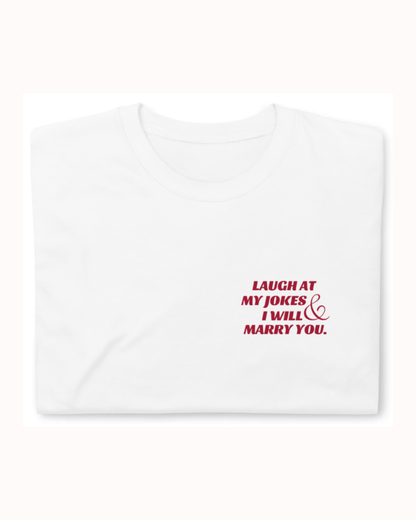 Folded white T-Shirt featuring the ironic phrase 'Laugh at my jokes and I will marry you'. Perfect for fans of funny merchandise, bold humor, and witty sarcasm. 