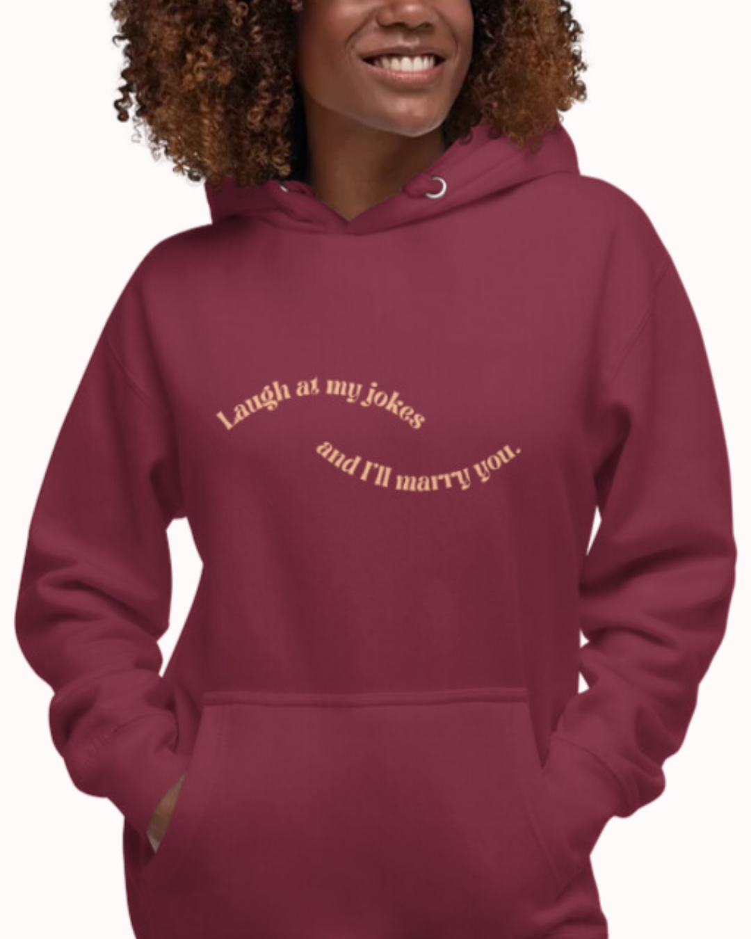 Front view of a maroon hoodie worn by a smiling woman, featuring the phrase 'Laugh at my jokes and I'll marry you' on the chest. Perfect for fans of funny merchandise, bold humor, and witty sarcasm.