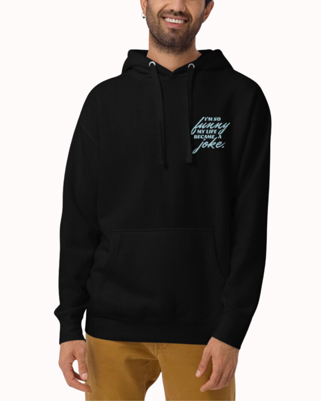 Front view of a black hoodie worn by a smiling man, featuring the phrase 'I'm so funny my life became a joke' on the chest and back. Perfect for fans of funny merchandise, bold humor, and witty sarcasm.