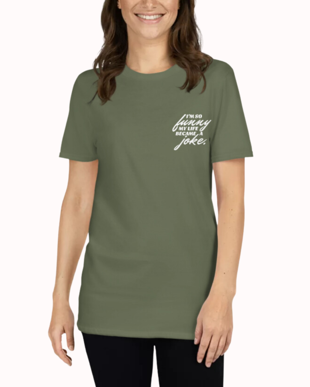 Front view of a military green T-Shirt worn by a smiling woman, featuring the phrase 'I'm so funny my life became a joke' on the chest and back. Perfect for fans of funny merchandise, bold humor, and witty sarcasm.