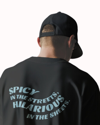 Back view of a black T-Shirt featuring the phrase 'Spicy in the streets, Hilarious in the sheets' on the back. Perfect for fans of funny merchandise, bold humor, and witty sarcasm.