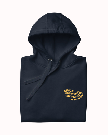 Folded navy blazer hoodie featuring the ironic phrase 'Spicy in the streets, Hilarious in the sheets'. Perfect for fans of funny merchandise, bold humor, and witty sarcasm.