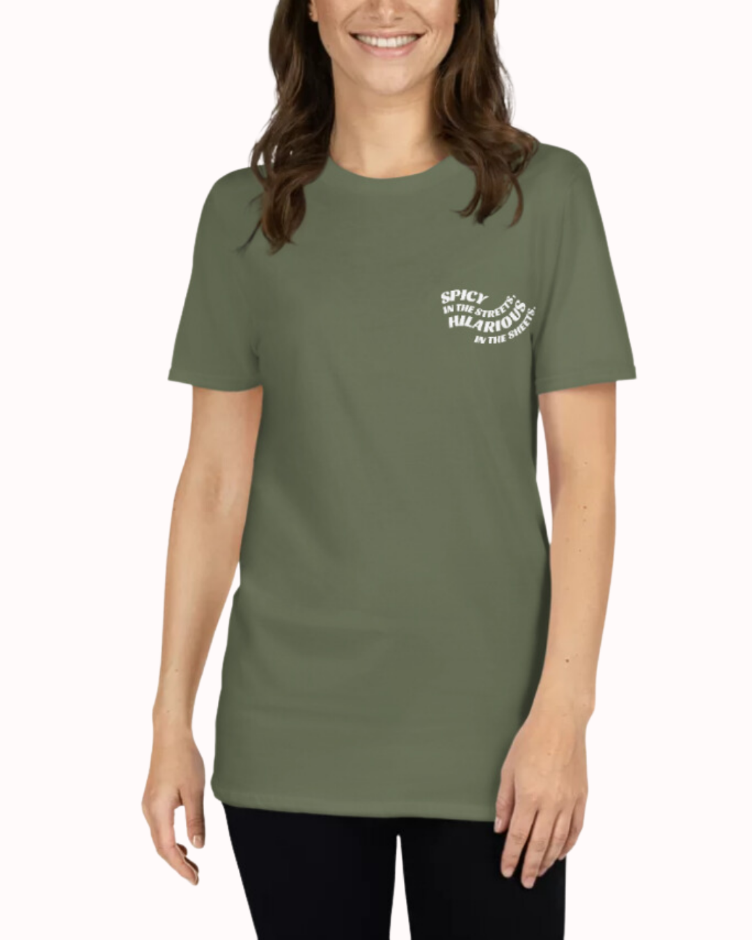 Front view of a military green T-Shirt worn by a smiling woman, featuring the phrase 'Spicy in the streets, Hilarious in the sheets' on the chest and back. Perfect for fans of funny merchandise, bold humor, and witty sarcasm.