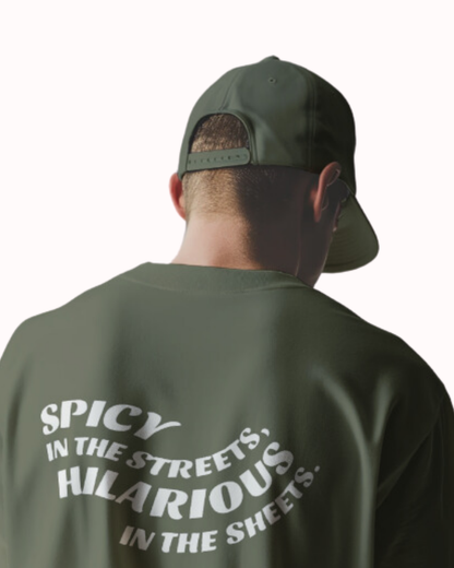 Back view of a military green T-Shirt featuring the phrase 'Spicy in the streets, Hilarious in the sheets' on the back. Perfect for fans of funny merchandise, bold humor, and witty sarcasm.