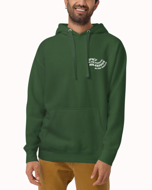 Front view of a forest green hoodie worn by a smiling man, featuring the phrase 'Spicy in the streets, Hilarious in the sheets' on the chest and back. Perfect for fans of funny merchandise, bold humor, and witty sarcasm.