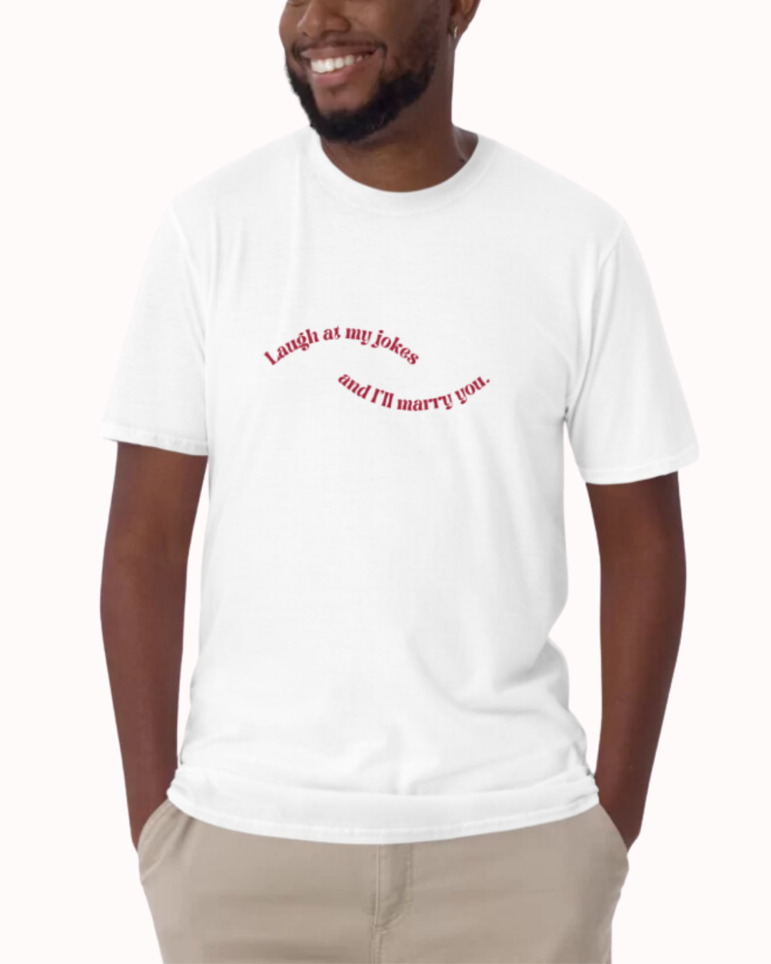 Front view of a white T-Shirt worn by a smiling man, featuring the phrase 'Laugh at my jokes and I will marry you' on the chest. Perfect for fans of funny merchandise, bold humor, and witty sarcasm. 