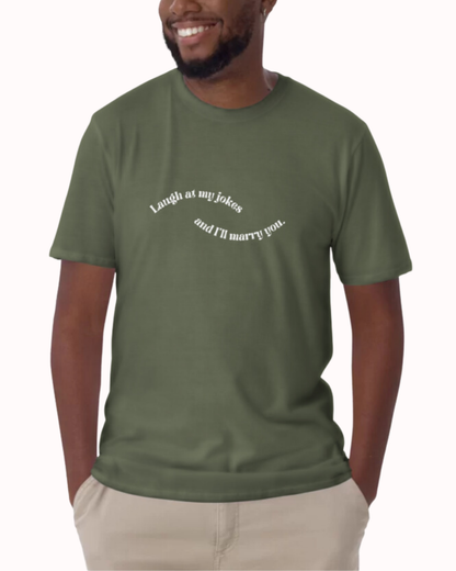 Front view of a military green T-Shirt worn by a smiling man, featuring the phrase 'Laugh at my jokes and I will marry you' on the chest. Perfect for fans of funny merchandise, bold humor, and witty sarcasm. 